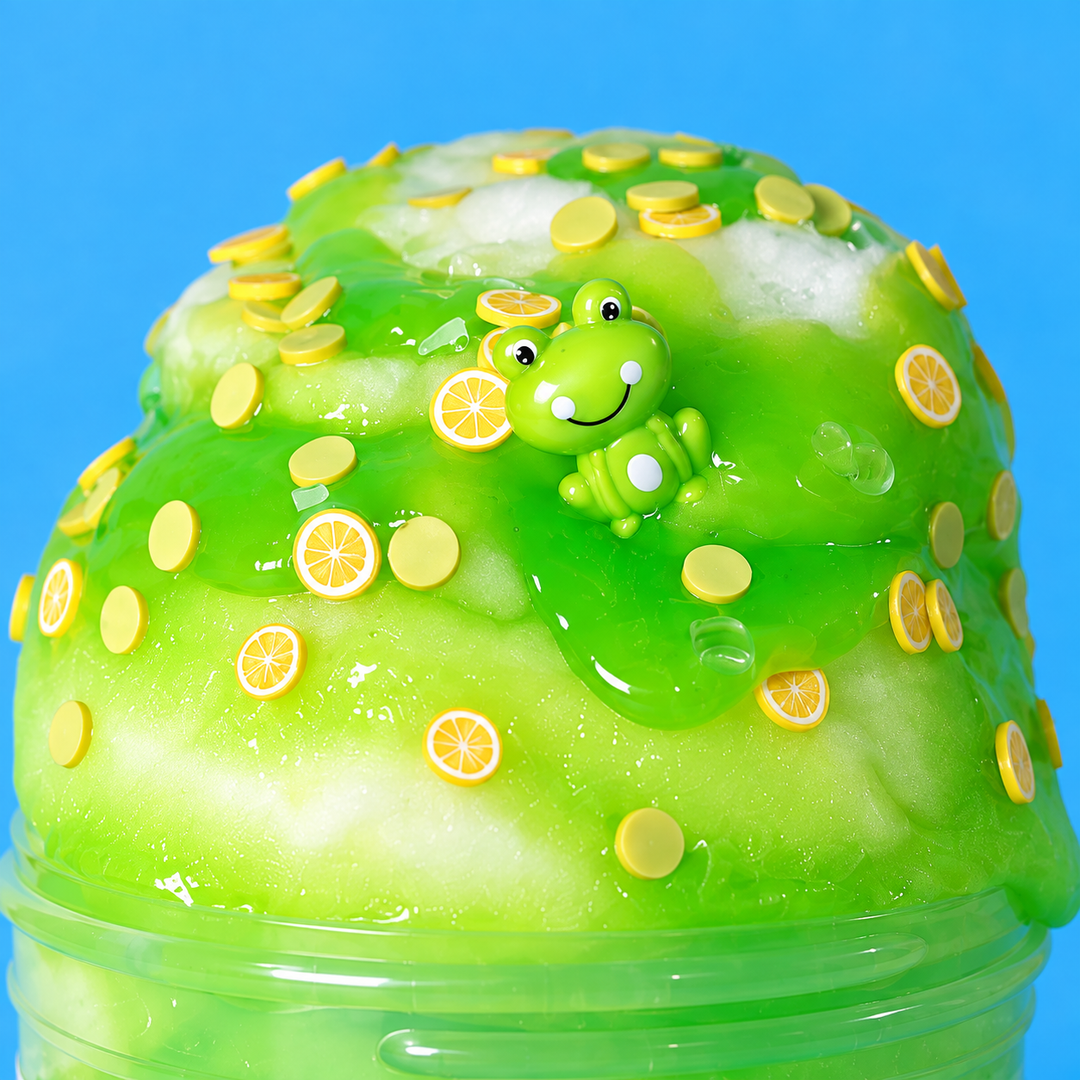 a close up on Slimepop Lime in the Clouds slime, with white ckud base slime and swirls os neon green jelly slime, lime slices, sprinkles and a green frog charm on a sky-blue background.