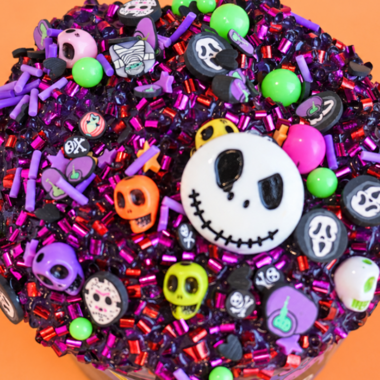 A closeup of halloween slime creation by slimepop, showing surface of a slime packed with haloween themed beads , colorful skulls nd neon green beads