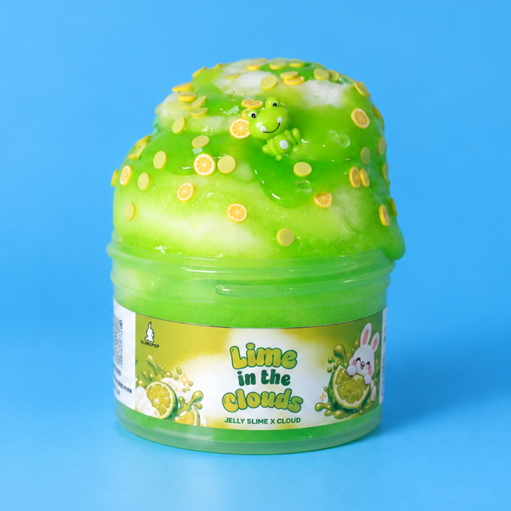 Slimepop Lime in the Clouds jar with white cloud slime, neon green jelly, lime slices, sprinkles and a green frog charm on a sky-blue background.