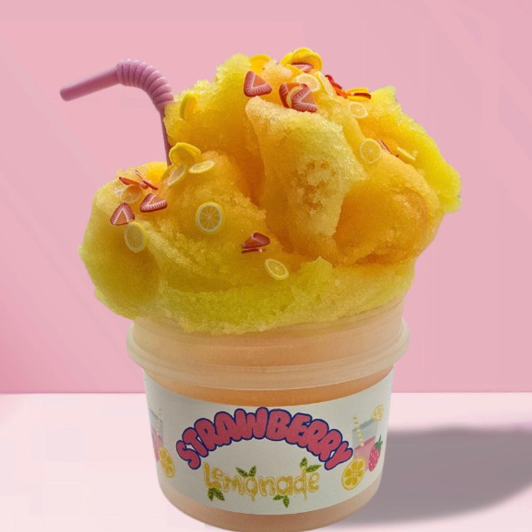 Yellow and pink icee slime with straw charm and strawberry and lemon polymer slices in a cup labeled 'Strawberry Lemonade' on a pink background.