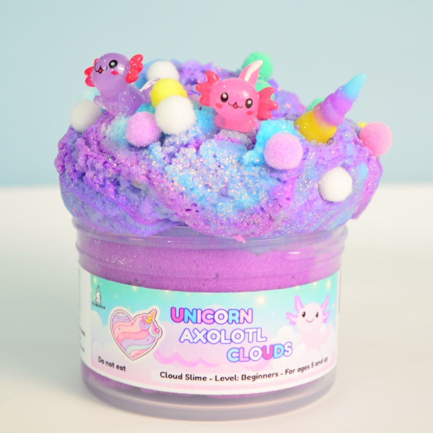 Jar of colorful cloud slime with axolotl and unicorn figurines on a light blue background